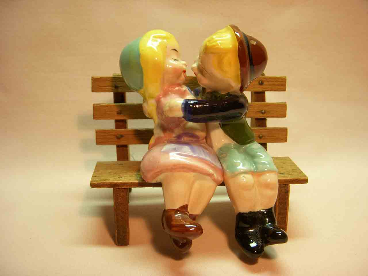 Boy and girl kissing sitting on wooden bench salt and pepper shaker